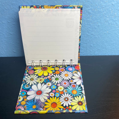 Small notebook with a colorful floral cover on a dark surface.