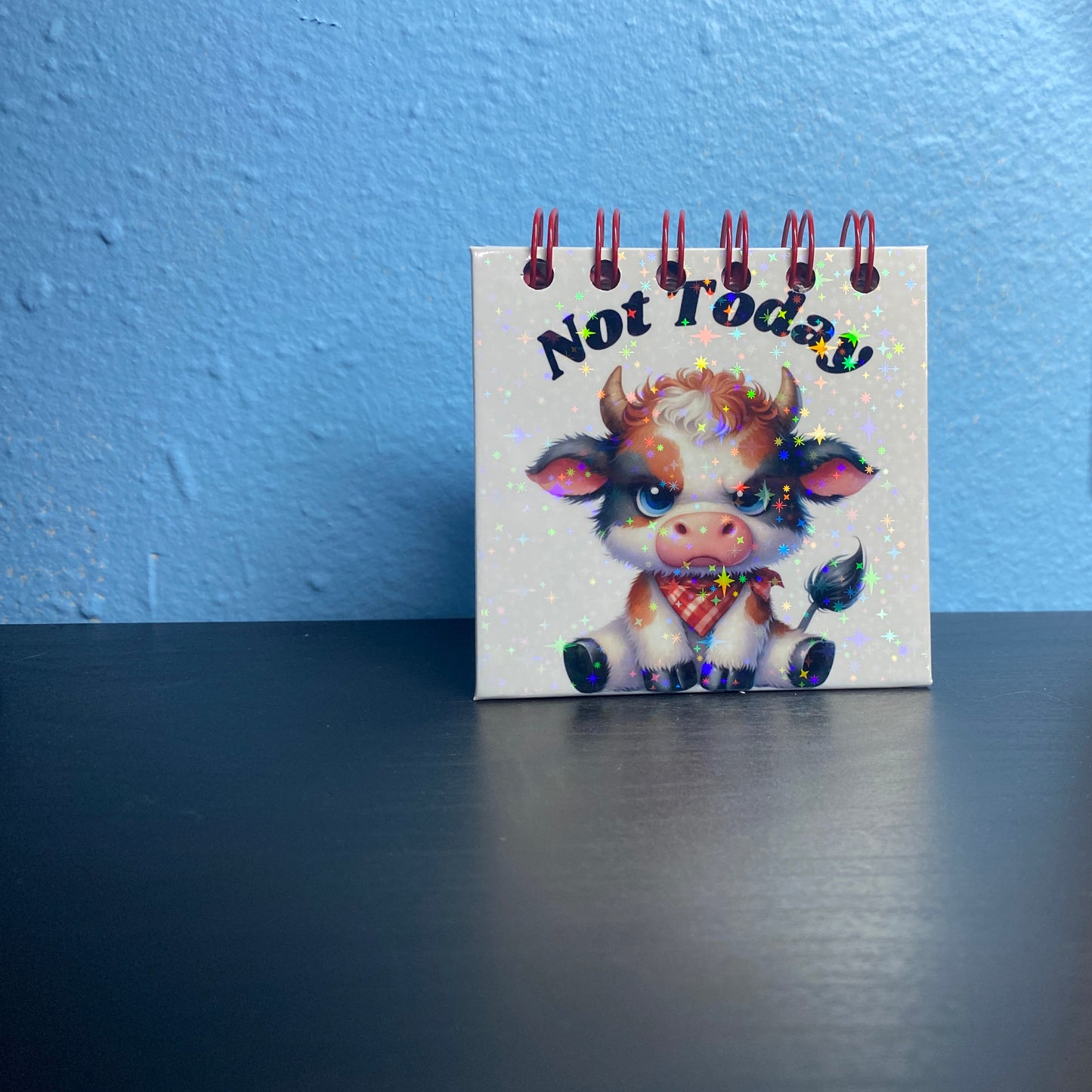 Small notepad with a cow illustration and 'Not Today' text on a blue wall background.