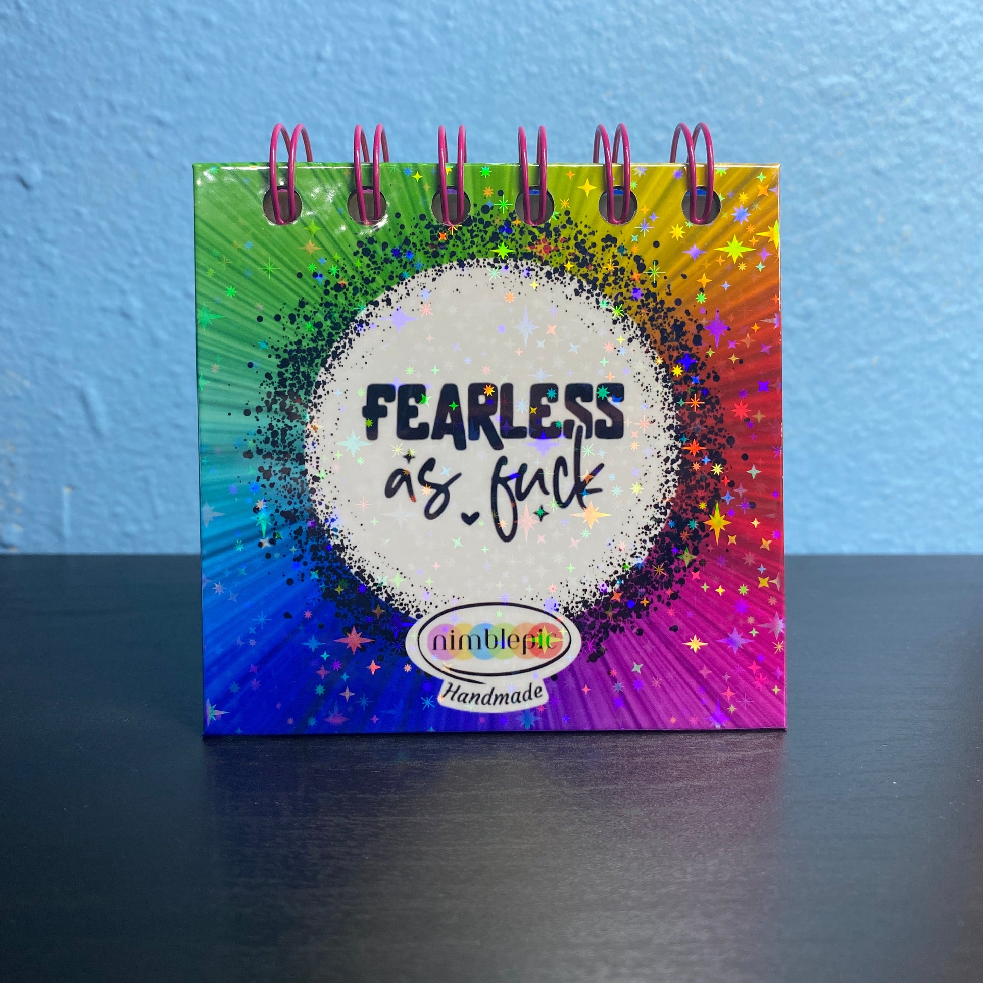 Small notebook with colorful spiral binding and text on a blue surface